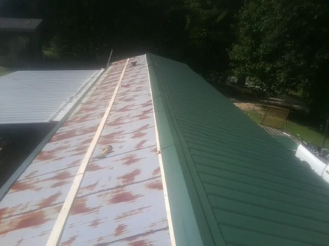 Old rusted panels beside newly installed green metal roofing — Wind Damage Roof Repair by Roofing Brothers in Palomar Mountain