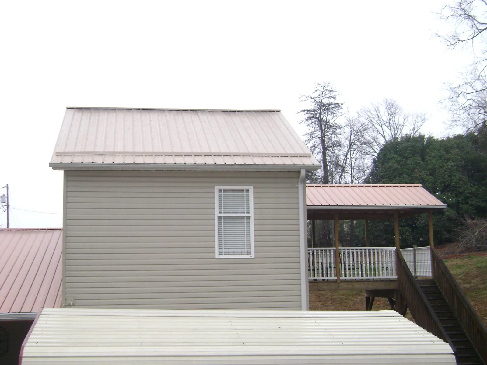 Tan metal roofs on a two story addition and attached porch, from a Roof Replacement job in Palomar Mountain