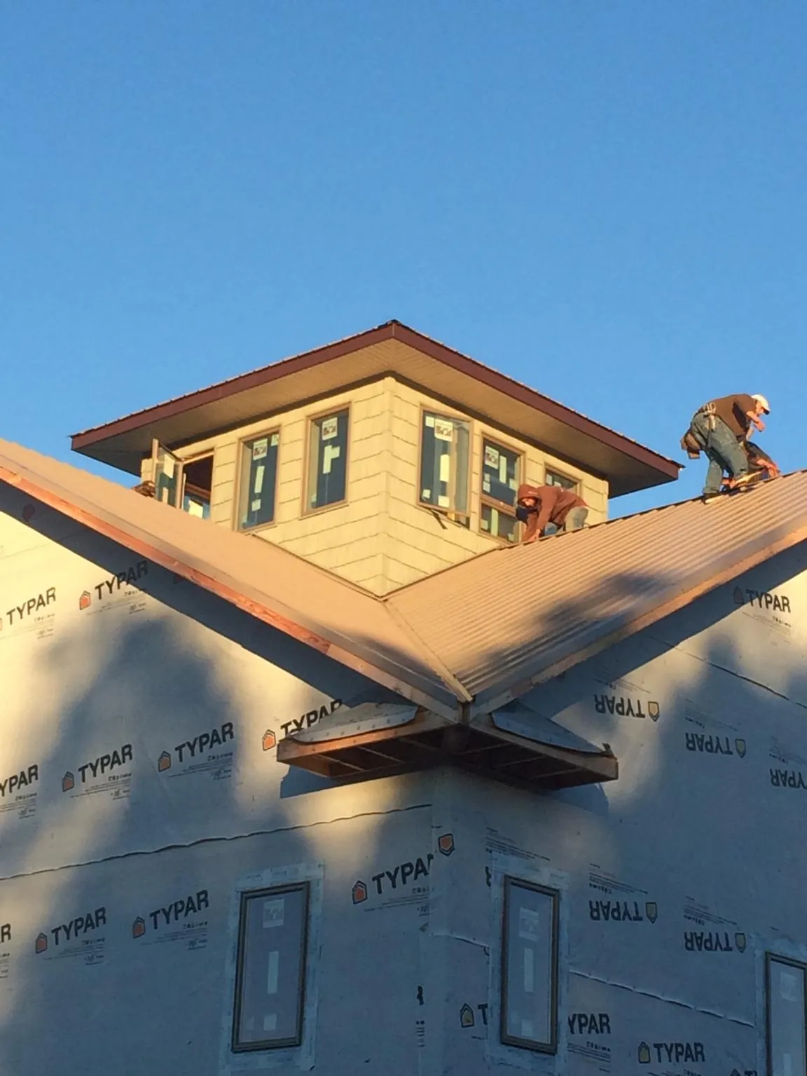 Roofers working around a rooftop cupola on a new metal roof at sunset — Roof Waterproofing in Palomar Mountain by Roofing Brothers